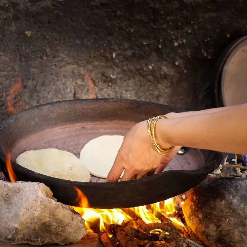 Préparation et cuisson du pain marocain artisanal dans un four en terre cuite.